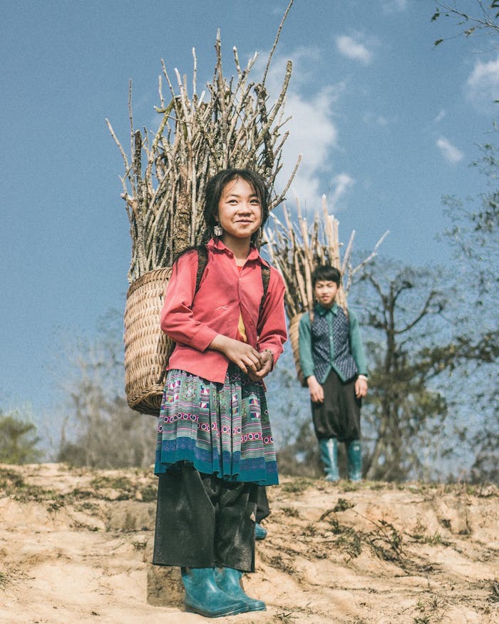 Two children carry firewood in baskets in the countryside of Lao Cai, Vietnam.